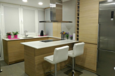 This is an example of a small contemporary galley eat-in kitchen in Other with an undermount sink, flat-panel cabinets, medium wood cabinets, quartz benchtops, stainless steel appliances and a peninsula.
