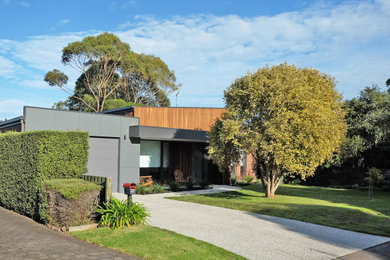 Cette image montre une façade de maison grise design en bois de taille moyenne et de plain-pied avec un toit plat et un toit en métal.