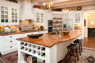 Trendy medium tone wood floor kitchen photo in Atlanta with an undermount sink, recessed-panel cabinets, white cabinets, wood countertops, stone tile backsplash and an island