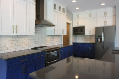 Large transitional l-shaped medium tone wood floor open concept kitchen photo in Indianapolis with an undermount sink, white cabinets, white backsplash, subway tile backsplash, stainless steel appliances and an island