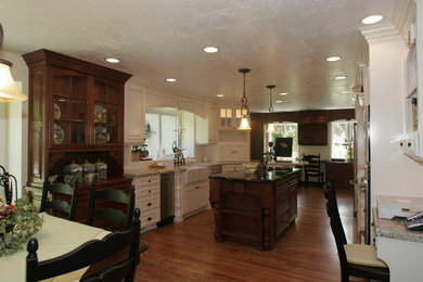 Large elegant galley medium tone wood floor eat-in kitchen photo in Salt Lake City with a farmhouse sink, recessed-panel cabinets, white cabinets, granite countertops, stainless steel appliances and an island