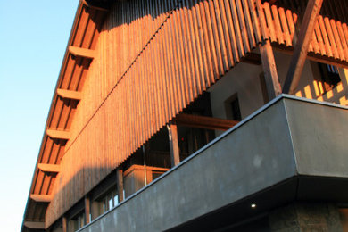 Inspiration pour un façade d'immeuble chalet en bois avec un toit à deux pans, un toit en métal et un toit gris.