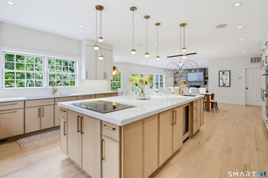 Inspiration for a huge modern u-shaped light wood floor and brown floor eat-in kitchen remodel in New York with a drop-in sink, flat-panel cabinets, white cabinets, marble countertops, white backsplash, marble backsplash, stainless steel appliances, an island and white countertops