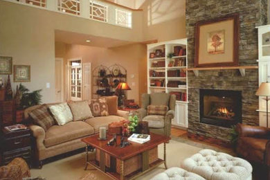Modelo de sala de estar abierta tradicional grande con paredes beige, suelo de madera clara, todas las chimeneas y marco de chimenea de piedra
