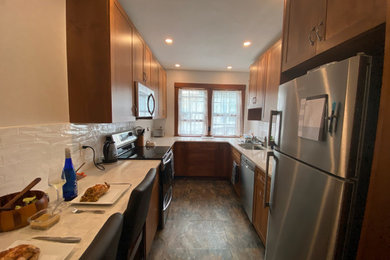 Enclosed kitchen - small transitional galley gray floor enclosed kitchen idea in Boston with a single-bowl sink, shaker cabinets, medium tone wood cabinets, quartzite countertops, white backsplash, subway tile backsplash, stainless steel appliances, no island and white countertops