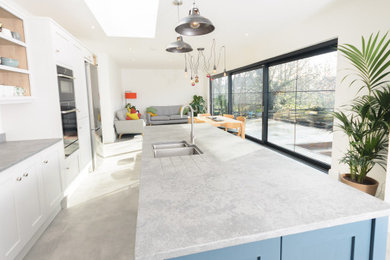 This is an example of a large contemporary kitchen/diner in Other with a submerged sink, shaker cabinets, blue cabinets, quartz worktops, grey splashback, an island, grey floors and grey worktops.