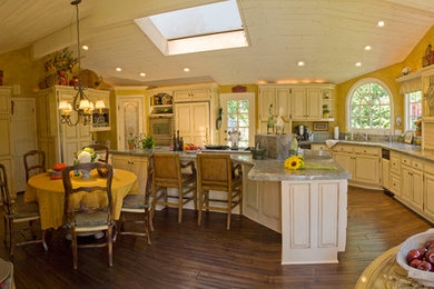 Inspiration for a large traditional u-shaped eat-in kitchen in Orange County with a drop-in sink, raised-panel cabinets, granite benchtops, green splashback, ceramic splashback, panelled appliances, dark hardwood floors, with island, brown floor, green benchtop and light wood cabinets.