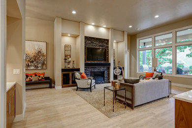 This is an example of a mid-sized transitional open concept living room in Portland with beige walls, light hardwood floors, a standard fireplace, a stone fireplace surround, a wall-mounted tv and beige floor.