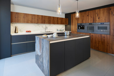 This is an example of a mid-sized contemporary kitchen in Essex with with island, flat-panel cabinets, dark wood cabinets, white splashback, stone slab splashback and multi-coloured benchtop.
