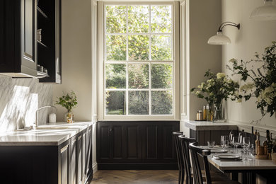 This is an example of a medium sized contemporary single-wall kitchen/diner in London with an integrated sink, beaded cabinets, black cabinets, marble worktops, white splashback, marble splashback, stainless steel appliances, painted wood flooring, no island, white worktops and a wood ceiling.