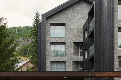 Imagen de fachada de piso gris contemporánea grande de tres plantas con revestimiento de piedra y tejado a dos aguas