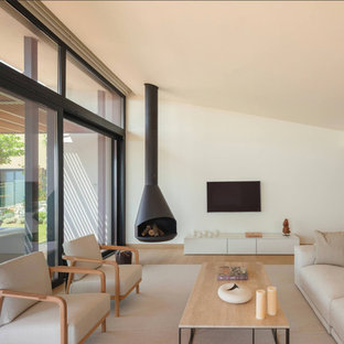 Mittelgroßes, Offenes Mediterranes Wohnzimmer mit weißer Wandfarbe, hellem Holzboden, Hängekamin, Kaminsims aus Metall, Wand-TV und beigem Boden in Sonstige