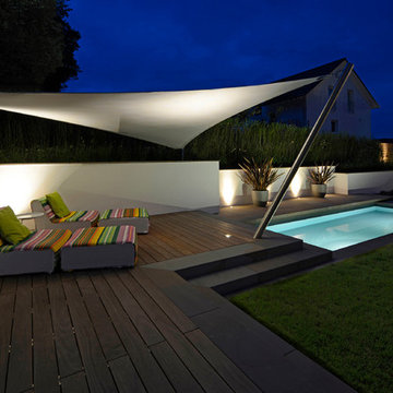 Sitzplatz mit beleuchtetem Sonnensegel vor der seitlichen Böschungsmauer