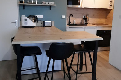 Kleine Moderne Küche mit Arbeitsplatte aus Holz, schwarzen Elektrogeräten und Kücheninsel in Toulouse