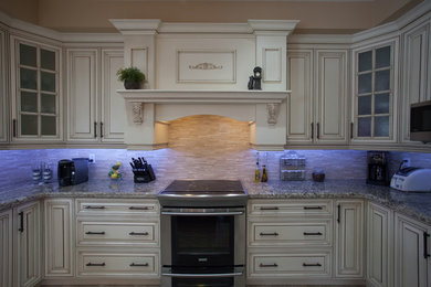 Eat-in kitchen - contemporary u-shaped eat-in kitchen idea in Toronto with glass-front cabinets, granite countertops, stone tile backsplash, stainless steel appliances and an island