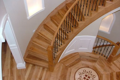 Photo of a large traditional wood spiral staircase in Denver with wood risers and metal railing.