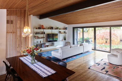 Ejemplo de salón abierto con paredes blancas, suelo de madera en tonos medios, chimenea de esquina y madera