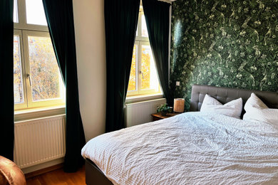 Mittelgroßes Modernes Hauptschlafzimmer mit grüner Wandfarbe, braunem Holzboden, braunem Boden und Tapetenwänden in Leipzig
