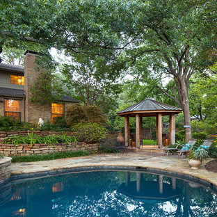 Klassischer Pool hinter dem Haus in Nierenform mit Natursteinplatten in Dallas