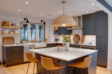 Inspiration for a large midcentury l-shaped kitchen/diner in Miami with a belfast sink, shaker cabinets, blue cabinets, engineered stone countertops, white splashback, mosaic tiled splashback, stainless steel appliances, light hardwood flooring, an island, orange floors and grey worktops.