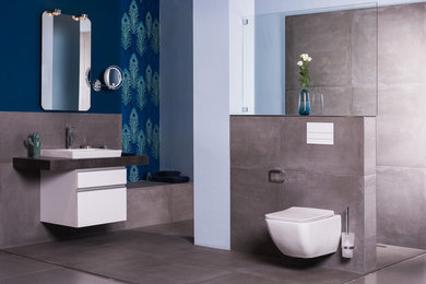 Mittelgroßes Modernes Badezimmer mit weißen Schränken, bodengleicher Dusche, Wandtoilette, grauen Fliesen, blauer Wandfarbe und offener Dusche in Berlin