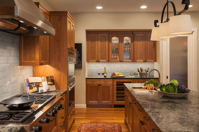 Large arts and crafts galley open plan kitchen in Minneapolis with an undermount sink, recessed-panel cabinets, medium wood cabinets, blue splashback, ceramic splashback, stainless steel appliances, medium hardwood floors and with island.