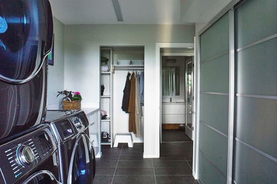 Galley black floor utility room photo in Toronto with a side-by-side washer/dryer
