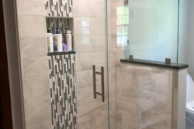 Modern bathroom in Boston with a corner shower, grey tiles, grey walls and a hinged door.