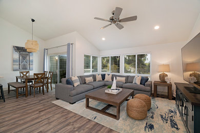 Mid-sized beach style open concept vinyl floor, brown floor and vaulted ceiling family room photo in San Diego with white walls, no fireplace and a tv stand