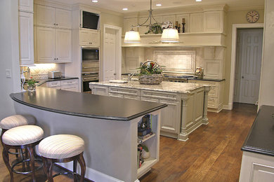 Traditional u-shaped kitchen in Dallas with recessed-panel cabinets, white cabinets, granite benchtops and with island.