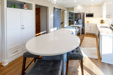 ミネアポリスにある高級な広いトランジショナルスタイルのおしゃれなキッチン (アンダーカウンターシンク、落し込みパネル扉のキャビネット、白いキャビネット、クオーツストーンカウンター、白いキッチンパネル、サブウェイタイルのキッチンパネル、シルバーの調理設備、無垢フローリング、茶色い床、白いキッチンカウンター) の写真