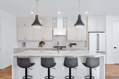 Inspiration for a transitional galley medium tone wood floor eat-in kitchen remodel in Denver with a farmhouse sink, shaker cabinets, quartz countertops, white backsplash, ceramic backsplash, white appliances, an island and white countertops
