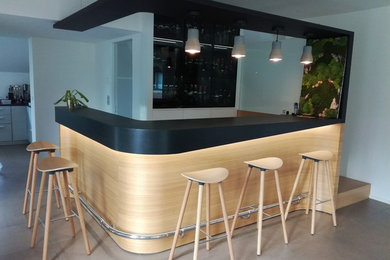 Aménagement d'un bar de salon moderne en L et bois clair de taille moyenne avec des tabourets, plan de travail en marbre et plan de travail noir.