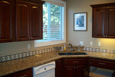 Kitchen - traditional kitchen idea in Portland with dark wood cabinets, beige backsplash, stainless steel appliances and an island