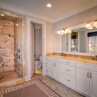 Foto di una grande stanza da bagno padronale chic con ante con riquadro incassato, ante bianche, doccia alcova, WC monopezzo, pareti grigie, pavimento in marmo, lavabo sottopiano, top in vetro, pavimento beige e porta doccia a battente