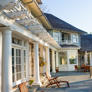 ニューヨークの巨大なヴィクトリアン調のおしゃれな裏庭のテラス (天然石敷き、日よけなし) の写真