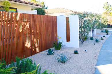 Inspiration for a mid-sized drought-tolerant and privacy front yard gravel and wood fence landscaping in Other.