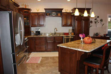 Inspiration for a mid-sized timeless l-shaped porcelain tile and beige floor eat-in kitchen remodel in Chicago with an island, raised-panel cabinets, dark wood cabinets, granite countertops, a double-bowl sink and stainless steel appliances