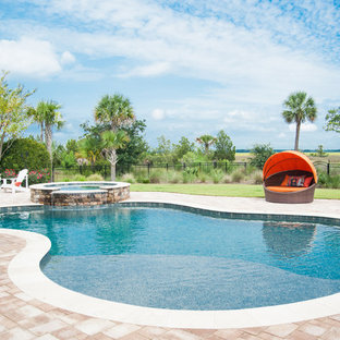Foto på en stor tropisk träningspool på baksidan av huset, med spabad och naturstensplattor