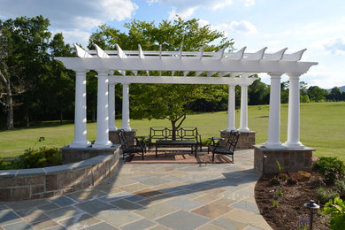 Photo of a large traditional backyard patio in DC Metro with natural stone pavers and a pergola.