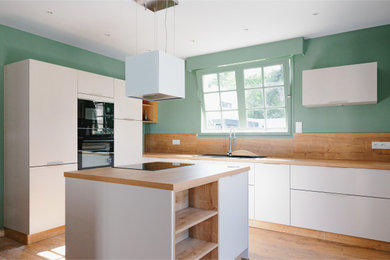 Imagen de cocinas en U beige y blanco contemporáneo con fregadero bajoencimera, puertas de armario blancas, salpicadero de madera y una isla