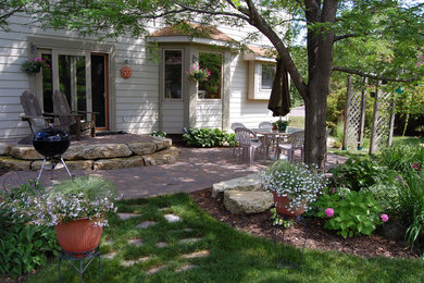 This is an example of a rustic partial sun backyard concrete paver landscaping in Minneapolis.