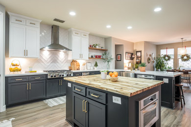 Example of a large minimalist u-shaped vinyl floor and gray floor open concept kitchen design in Sacramento with a farmhouse sink, shaker cabinets, black cabinets, quartz countertops, white backsplash, ceramic backsplash, stainless steel appliances, two islands and white countertops