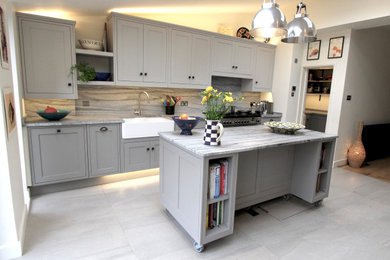 This is an example of a medium sized contemporary kitchen/diner in London with a belfast sink, shaker cabinets, grey cabinets, granite worktops, grey splashback, marble splashback, stainless steel appliances, ceramic flooring, an island, grey floors and grey worktops.
