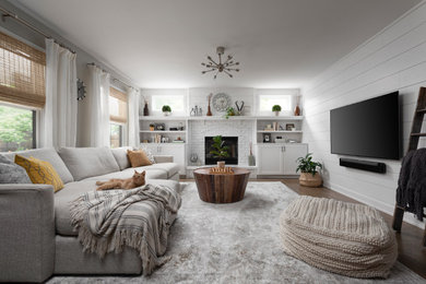 Example of a mid-sized transitional open concept medium tone wood floor, brown floor and shiplap wall family room design in Chicago with white walls, a standard fireplace, a brick fireplace and a wall-mounted tv