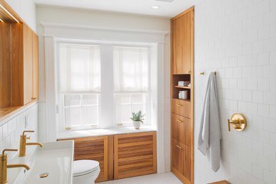 This is an example of a mid-sized modern master bathroom in Philadelphia with flat-panel cabinets, medium wood cabinets, an open shower, a one-piece toilet, white tile, porcelain tile, white walls, porcelain floors, a trough sink, engineered quartz benchtops, white floor, an open shower and white benchtops.