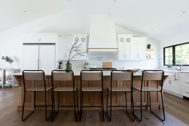 Example of a huge beach style l-shaped light wood floor and brown floor eat-in kitchen design in Toronto with an undermount sink, shaker cabinets, white cabinets, quartz countertops, white backsplash, subway tile backsplash, stainless steel appliances, an island and white countertops
