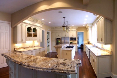 Huge elegant u-shaped dark wood floor open concept kitchen photo in Cleveland with white cabinets, granite countertops, stainless steel appliances, two islands, a single-bowl sink and raised-panel cabinets