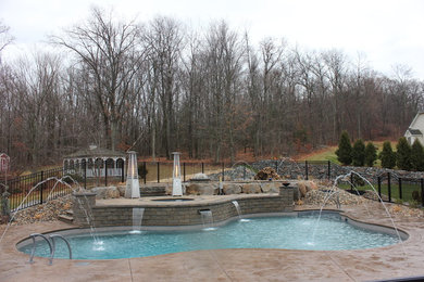 Trendy backyard stamped concrete and custom-shaped pool fountain photo in Bridgeport