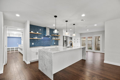 Large transitional single-wall open plan kitchen in Dallas with an undermount sink, shaker cabinets, white cabinets, marble benchtops, blue splashback, subway tile splashback, stainless steel appliances, dark hardwood floors, with island, brown floor and white benchtop.